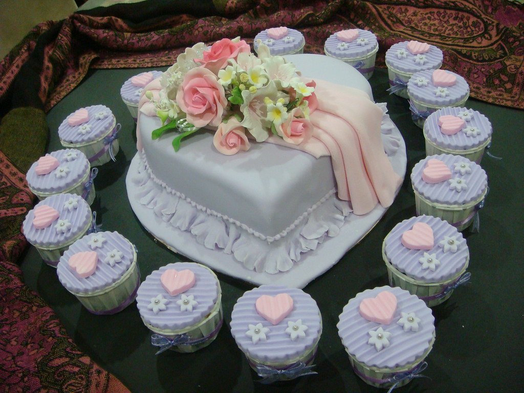 A lilac heart cake surrounded by lilac cupcakes